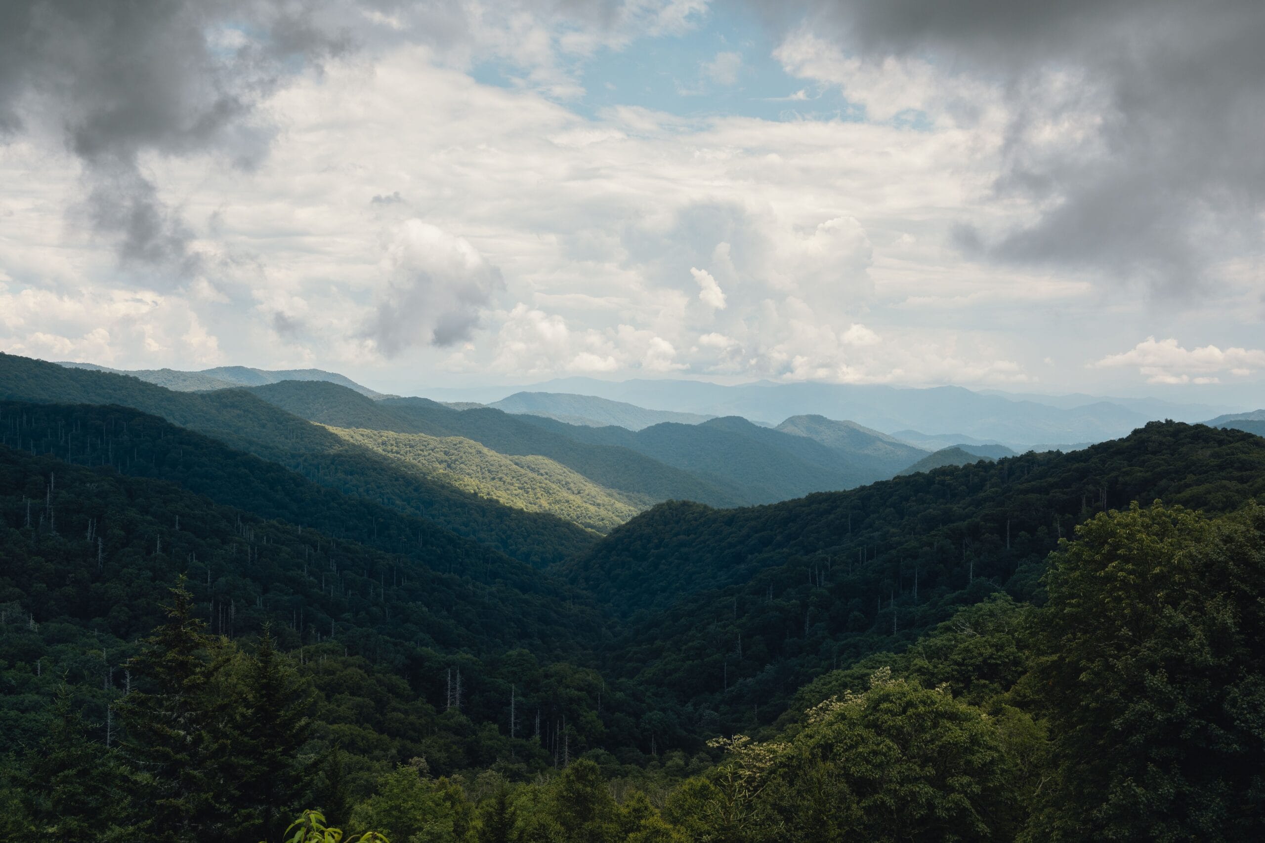 Forested Appalachian ridges under heavy cloud, the hill country terrain typical of Wetzel County, West Virginia, where Marcellus units are drilled beneath fragmented family mineral tracts