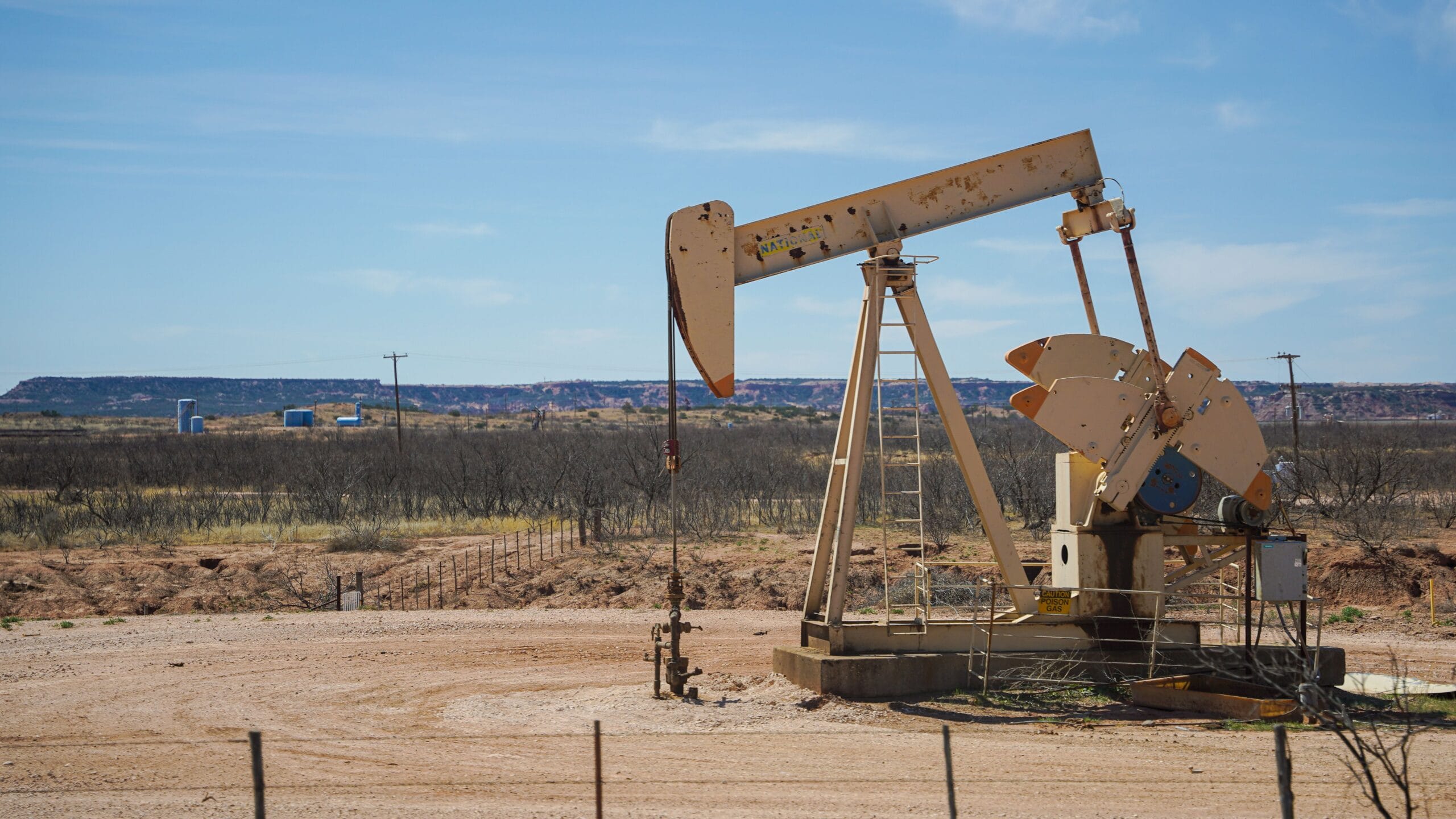 An aging pumping unit on a well pad in high-desert mesa country, typical of the long-lived San Juan Basin production that pays Rio Arriba County, New Mexico royalty owners