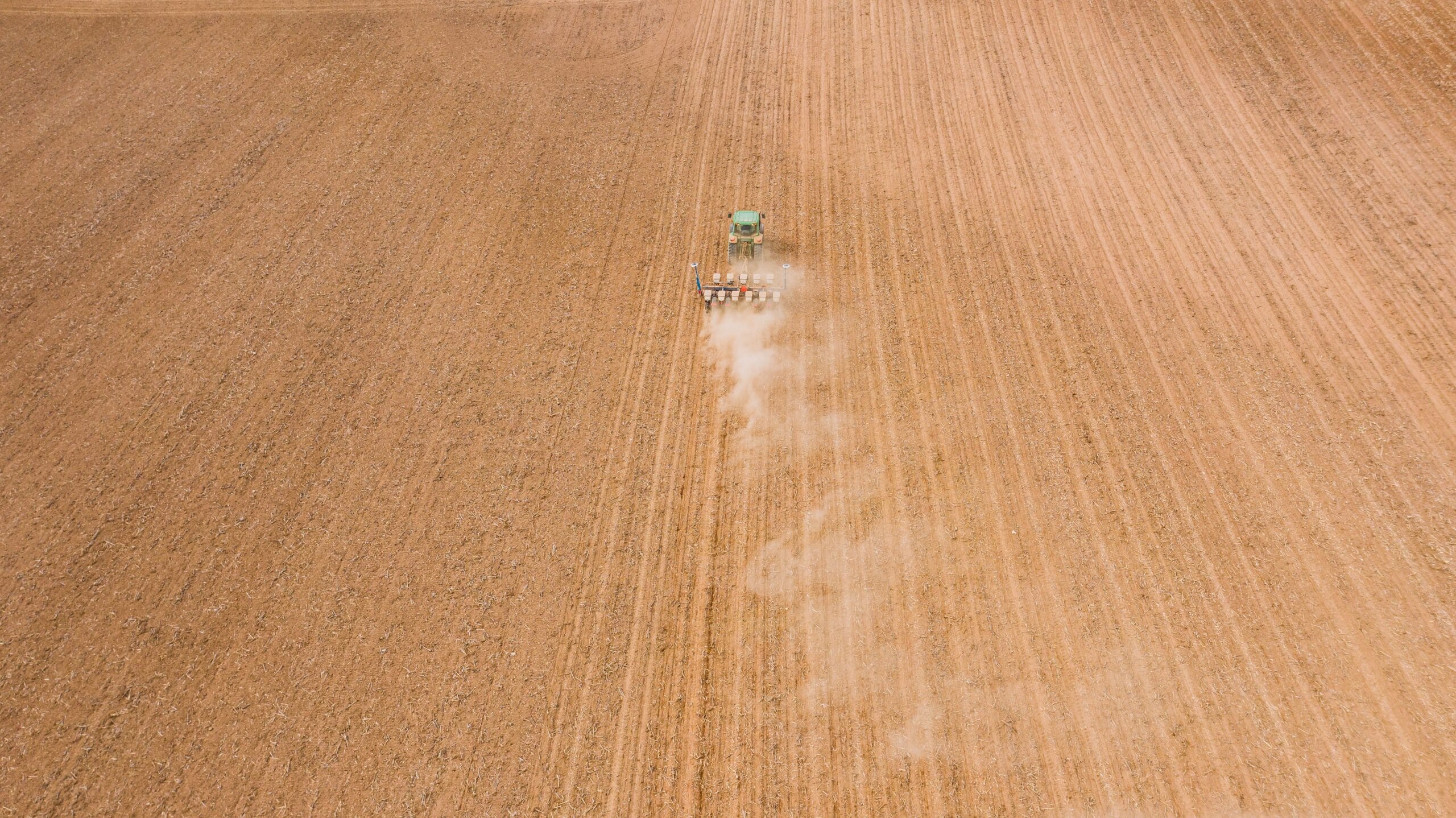 Aerial view of a tractor working a large open field, similar to the farmland tracts that overlie Haynesville Shale acreage in southern Caddo Parish, Louisiana