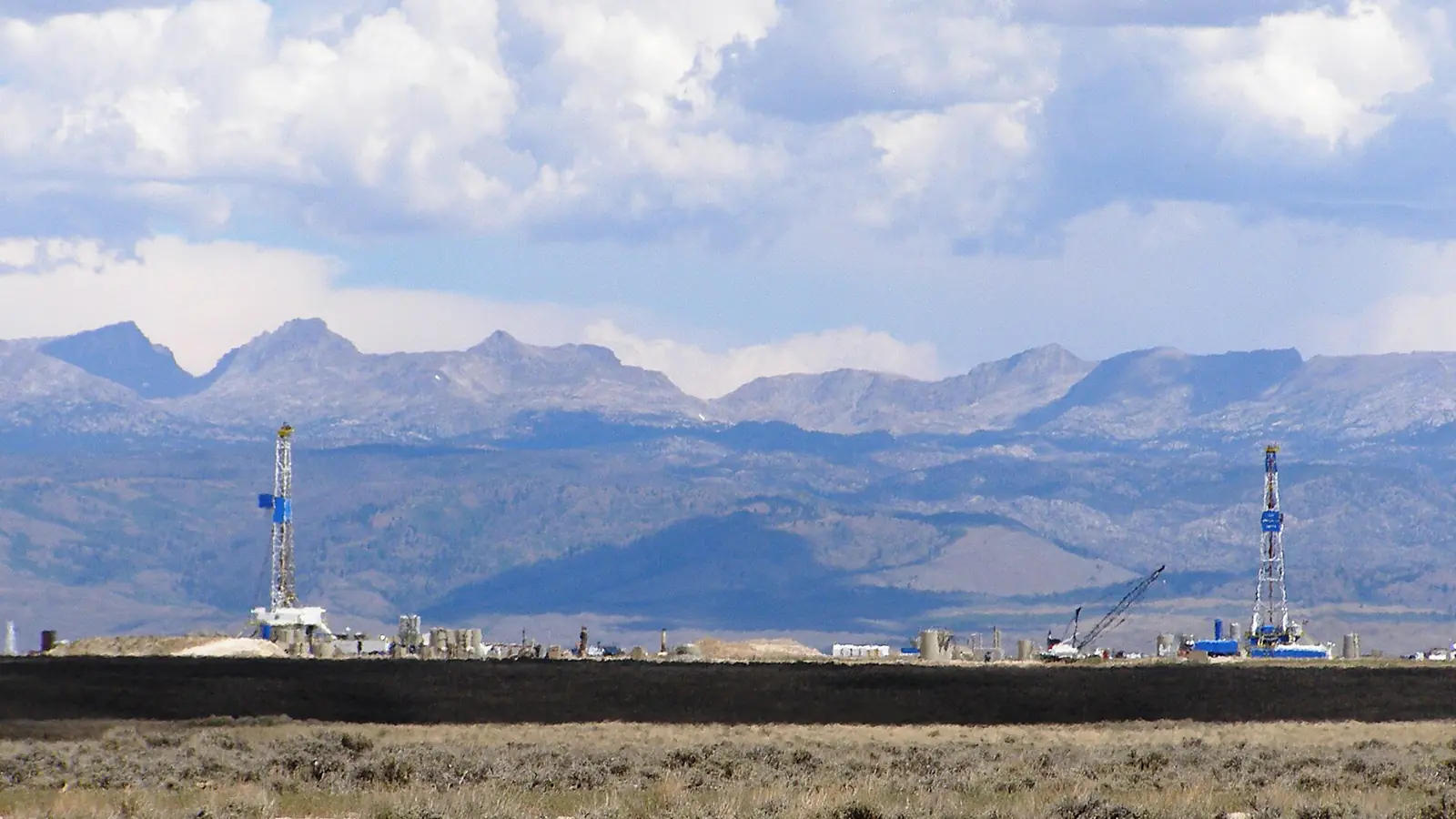 Two drilling rigs on the sagebrush plain below the Wind River Range, the setting of the Pinedale Anticline gas field in Sublette County, Wyoming